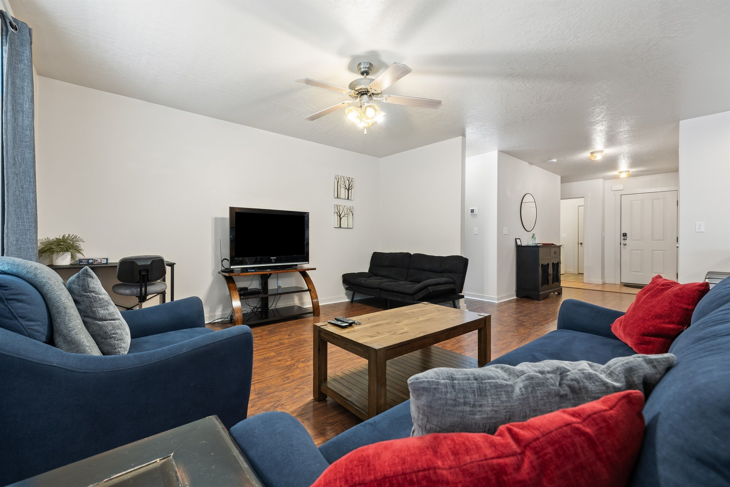A living room with a ceiling fan, a flat-screen TV, and two sofas.