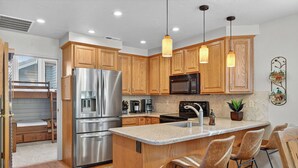 A modern kitchen with wooden cabinets, stainless steel appliances, and a central island with bar stools.