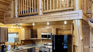 Una cocina amplia con detalles de madera, una isla central y un refrigerador negro.