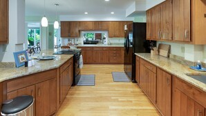Eine moderne Küche mit Holzschränken, Granit Arbeitsplatten und einer zentralen Kochinsel.