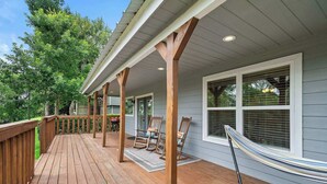 A wooden deck with a hammock, rocking chairs, and a covered porch area. - Riverfront Retreat w/ Decks & Views (Baytown)