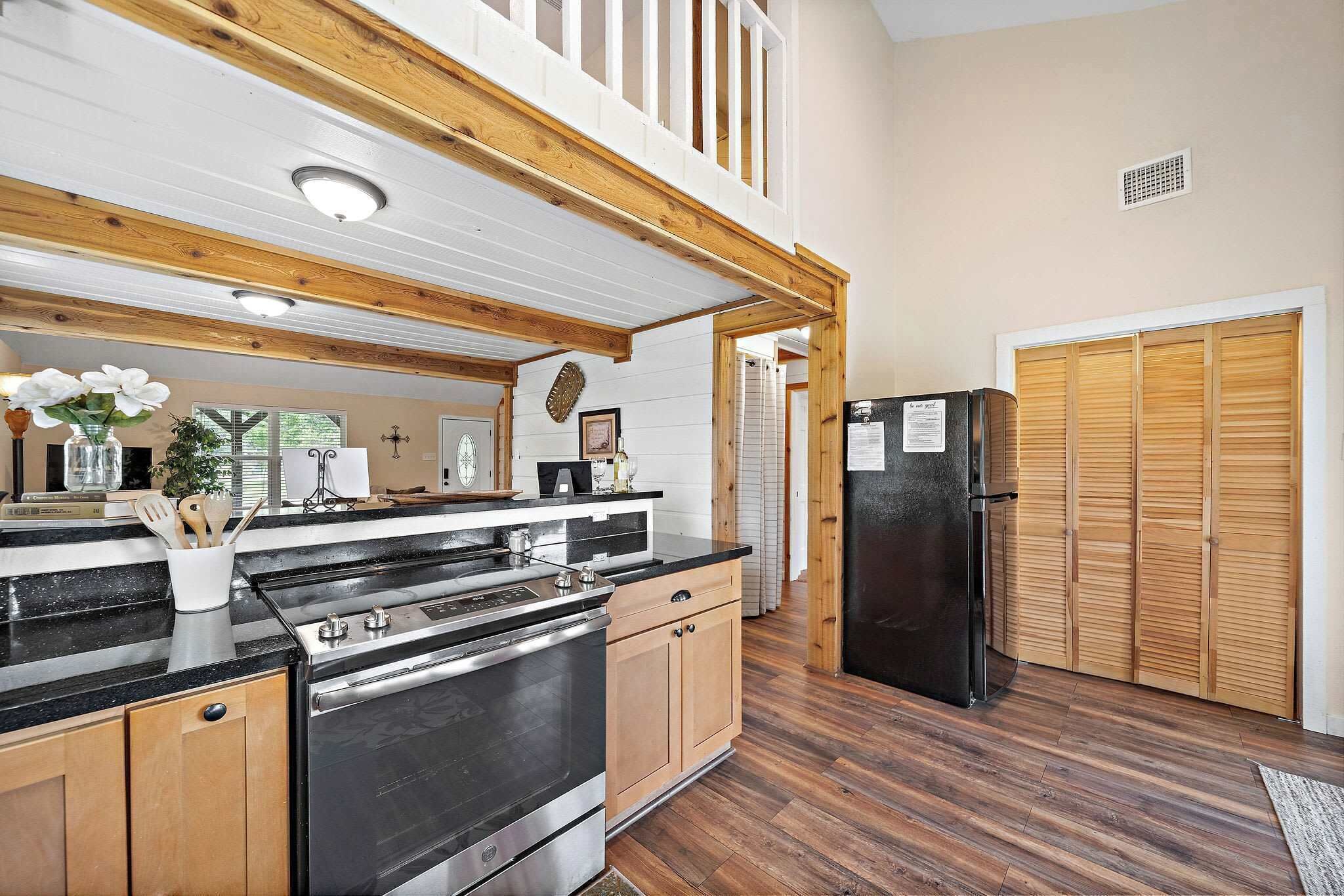 Une cuisine avec des meubles de rangement en bois, un réfrigérateur noir et un plafond en bois.