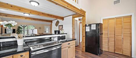 Une cuisine avec des meubles de rangement en bois, un réfrigérateur noir et un plafond en bois.