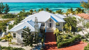 A beachfront property with a white building, a red pathway, and a view of the ocean. - Private Beachfront Luxury Estate pool with waterfall free concierge – Sleeps 16 (North Caicos)