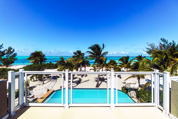 A pool with a view of a beach and palm trees.