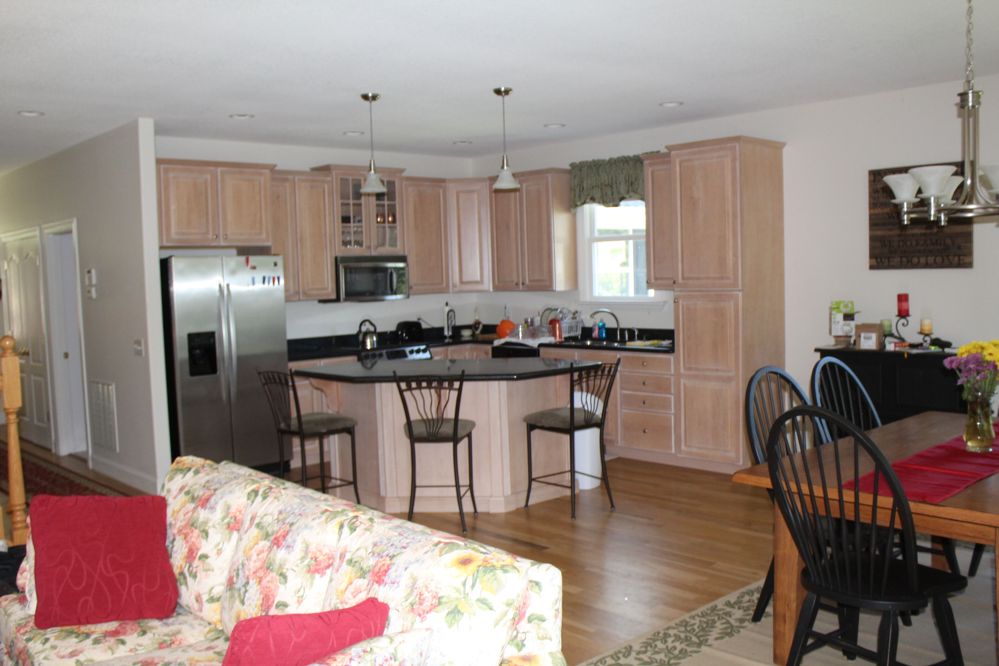A modern kitchen with wooden cabinets, stainless steel appliances, and a central island with chairs.