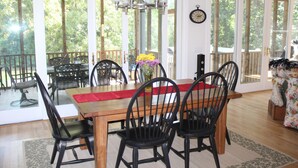 Een eetruimte met een houten tafel, zwarte stoelen en een rode loper.
