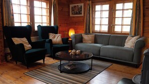 A cozy living room with a sofa, two armchairs, a coffee table, and a rug. - Log cabin for 4 + 2 people, 80m2 in the middle of the forest between 2 lakes (Hallaryd)