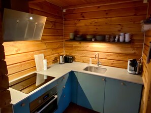 A compact kitchen with a built-in oven, a sink, and a coffee maker. - Log cabin for 4 + 2 people, 80m2 in the middle of the forest between 2 lakes (Hallaryd)
