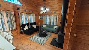A cozy log cabin interior with a sofa, two armchairs, a coffee table, and a fireplace. - Log cabin for 4 + 2 people, 80m2 in the middle of the forest between 2 lakes (Hallaryd)