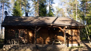 A wooden cabin with a porch, picnic table, and chairs. - Log cabin for 4 + 2 people, 80m2 in the middle of the forest between 2 lakes (Hallaryd)