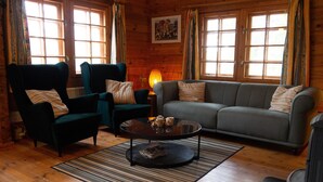 A cozy living room with a sofa, two armchairs, a coffee table, and a fireplace. - Log cabin for 4 + 2 people, 80m2 in the middle of the forest between 2 lakes (Hallaryd)