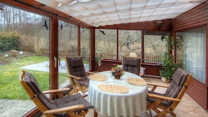 A sunroom with a table and chairs, large windows, and a view of the backyard. - Family-friendly holiday paradise 120m² modern equipment, close to the beach (500m) (timmendorfer strand)