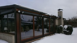 A glass-enclosed structure with a brick base, a chimney, and snow accumulation. - Family-friendly holiday paradise 120m² modern equipment, close to the beach (500m) (timmendorfer strand)