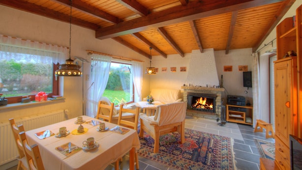 A cozy room with a fireplace, a dining table set with tea cups, and a view of the garden through the window. - Family-friendly holiday paradise 120m² modern equipment, close to the beach (500m) (timmendorfer strand)