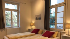 A double bed with two pillows, a bedside table with a lamp, and a window with curtains. - 2-room apartment II "Am Nonnenhaus", old town near the university for up to 4 people (Tübingen)