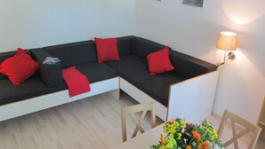 A modern living room with a sectional sofa, red cushions, a table with a vase of flowers, and a lamp. - 2-room apartment II "Am Nonnenhaus", old town near the university for up to 4 people (Tübingen)