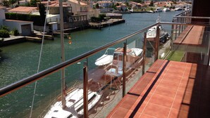 Een balkon met uitzicht op een jachthaven, boten afgemeerd en gebouwen op de achtergrond.