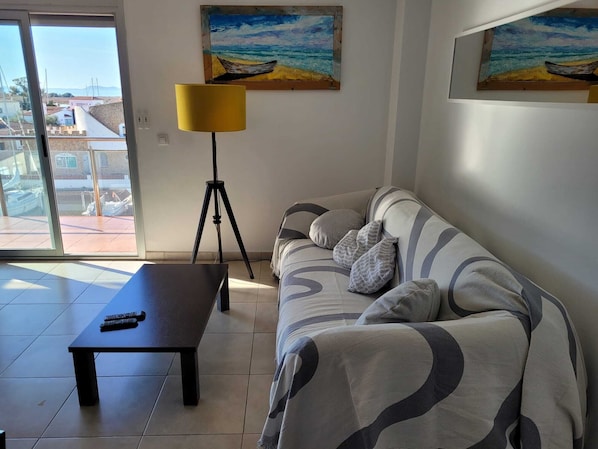 Una sala de estar con un sofá, una mesa de centro, una lámpara y dos cuadros en la pared.