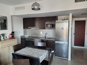 Una cocina moderna con armarios oscuros, un refrigerador de acero inoxidable, un microondas y una estufa a gas.
