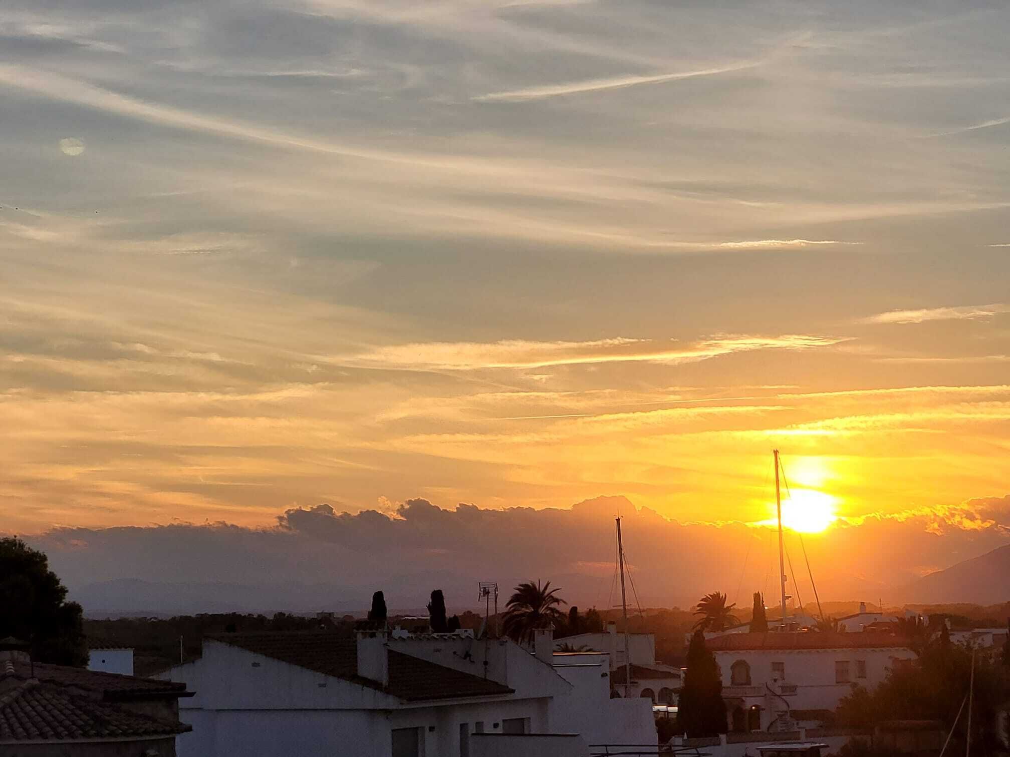 A sunset over a residential area with buildings and a mountain in the background.