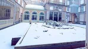 Un patio con suelo cubierto de nieve y edificios con ventanas arqueadas y balcones.