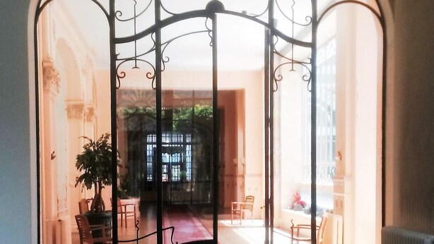 Una habitación amplia con suelo de baldosas, un arco grande en la entrada y una planta en maceta cerca.