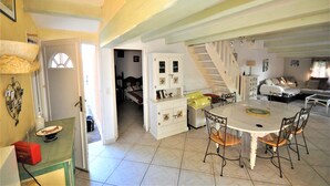 A spacious living area with a dining table, chairs, and a staircase leading to an upper floor. - Cosy air-conditioned vacation home by the sea, free bikes (Saint-Cyprien)