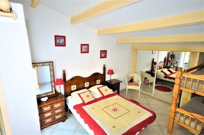 A bedroom with a wooden bed, a dresser, a mirror, and a chair.
