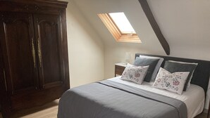 A bedroom with a large bed, a nightstand, a dresser, and a skylight. - Le cottage de Soiz vacation rental  (Bannalec)