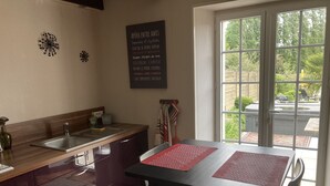 A kitchen with a wooden countertop, a sink, and a dining table with chairs. There is a window with a view of the outdoors. - Le cottage de Soiz vacation rental  (Bannalec)