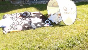 A stone building with a balcony, a table with chairs, and a baby tent on the grass. - 3 * appt, 5 people in the heart of the resort, open to hikers out of season (Les Avanchers-Valmorel)
