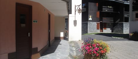 A hotel entrance with a stone-paved pathway, a wooden door, and a flower planter.