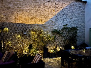Un mur de pierre, une clôture en métal et des plantes en pot, le tout dans un décor extérieur.