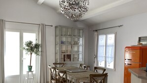 A dining area with a wooden table and chairs, a cabinet with glass doors, a potted plant, and a vintage refrigerator.