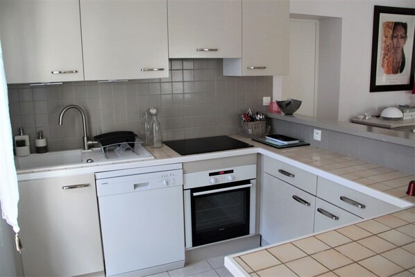 A modern kitchen with white cabinets, a dishwasher, an oven, and a sink.