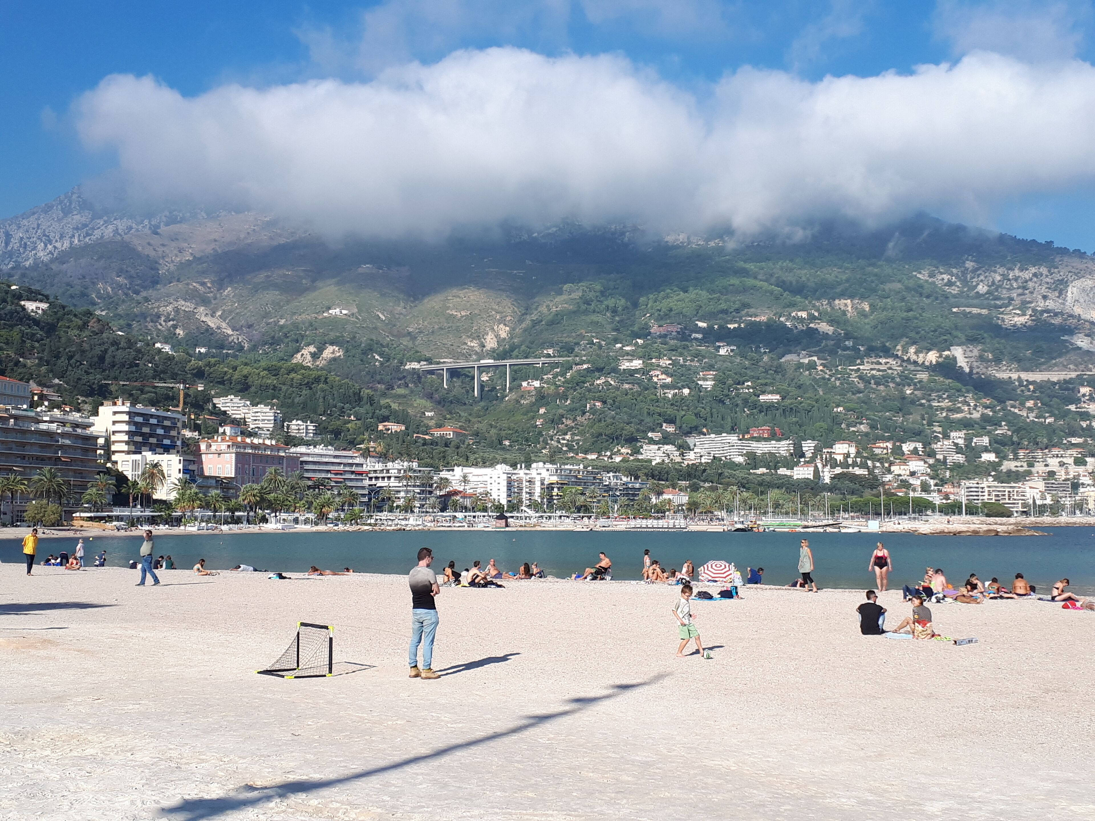 A beach with people relaxing and a mountain in the background.