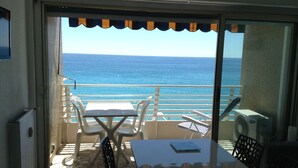 A balcony with a table and chairs, overlooking the sea. - --- Beachfront Studio ---- (Menton)