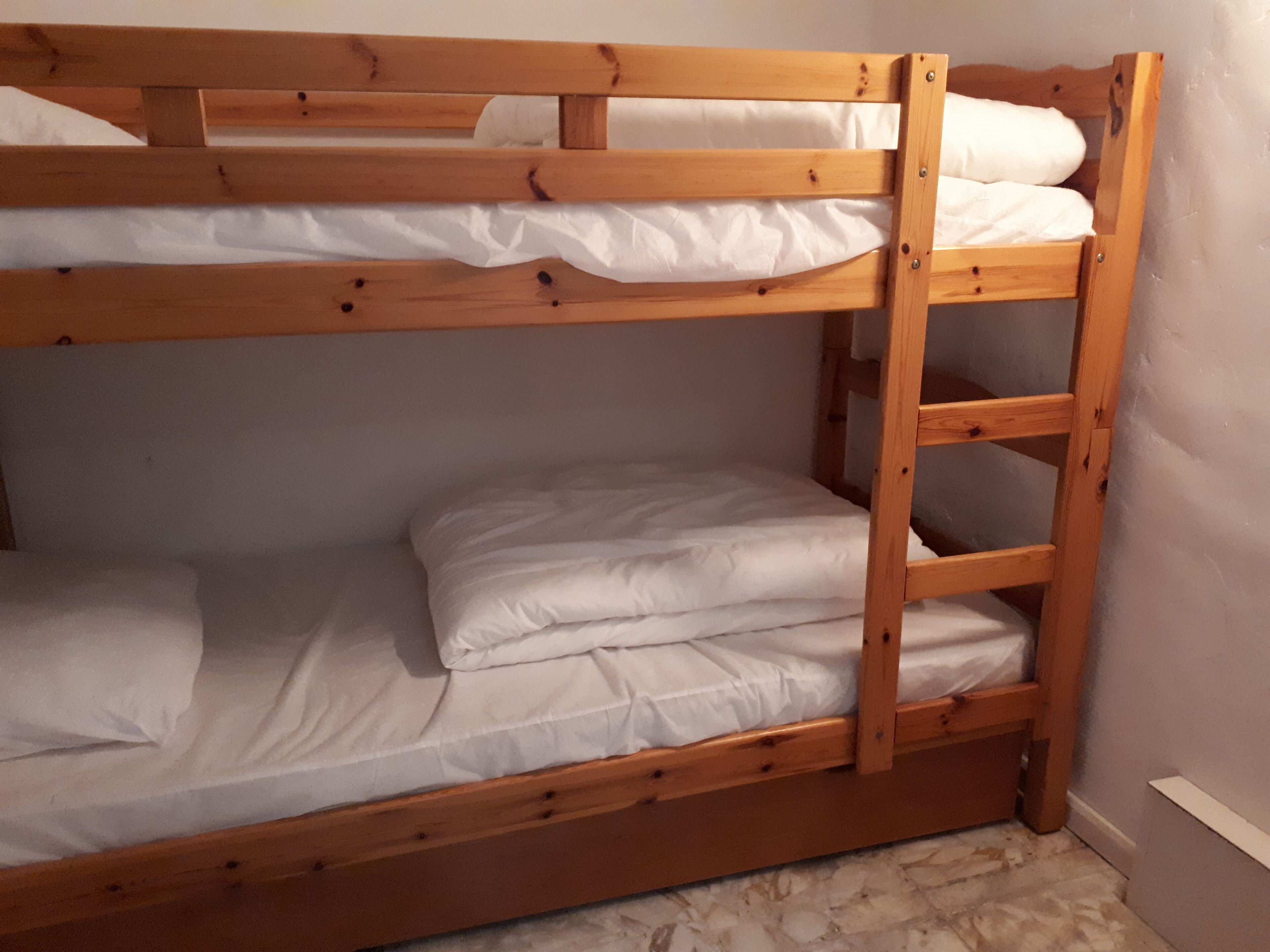 A bunk bed with two levels, each with white bedding.