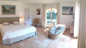 Una camera da letto con un letto grande, due comodini con lampade, una sedia in vimini e una porta che dà su uno spazio all'aperto.