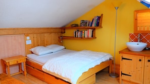 Un dormitorio acogedor con una cama de madera, una mesita de noche, una estantería, una lámpara de pie y un baño con lavabo.
