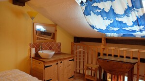 A cozy attic bedroom with a wooden bunk bed, a white basin sink, and a mirror above it.