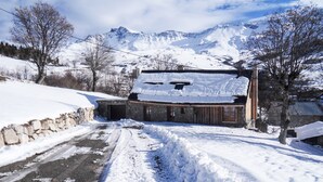 A snow-covered rural road leading to a stone building with a wooden roof, surrounded by snow-covered fields and mountains in the background. - Alpine chalet, near ski resort, for 10 people, completely renovated. (Montgellafrey)