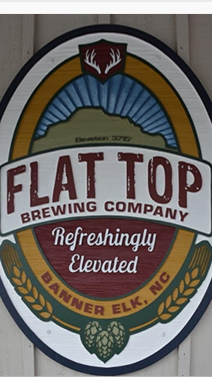 A circular sign with the text "FLAT TOP BREWING COMPANY" and "REFRESHINGLY ELEVATED" along with a logo featuring a shield and a horn.
