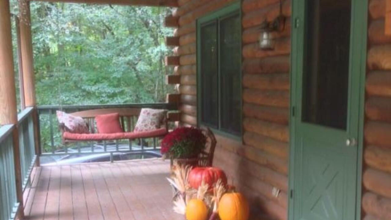 Eine Holzhütte mit Veranda, einer Bank und einer Tür.