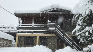 A traditional wooden building with a snow-covered roof and steps leading up to the entrance.