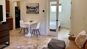 Un salon moderne comprenant un coin repas, un canapé, une table basse et une cuisine équipée d’un réfrigérateur et d’un four à micro-ondes.
