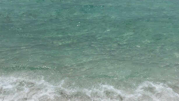 Une plage à l’eau turquoise et limpide, où les vagues sont douces.
