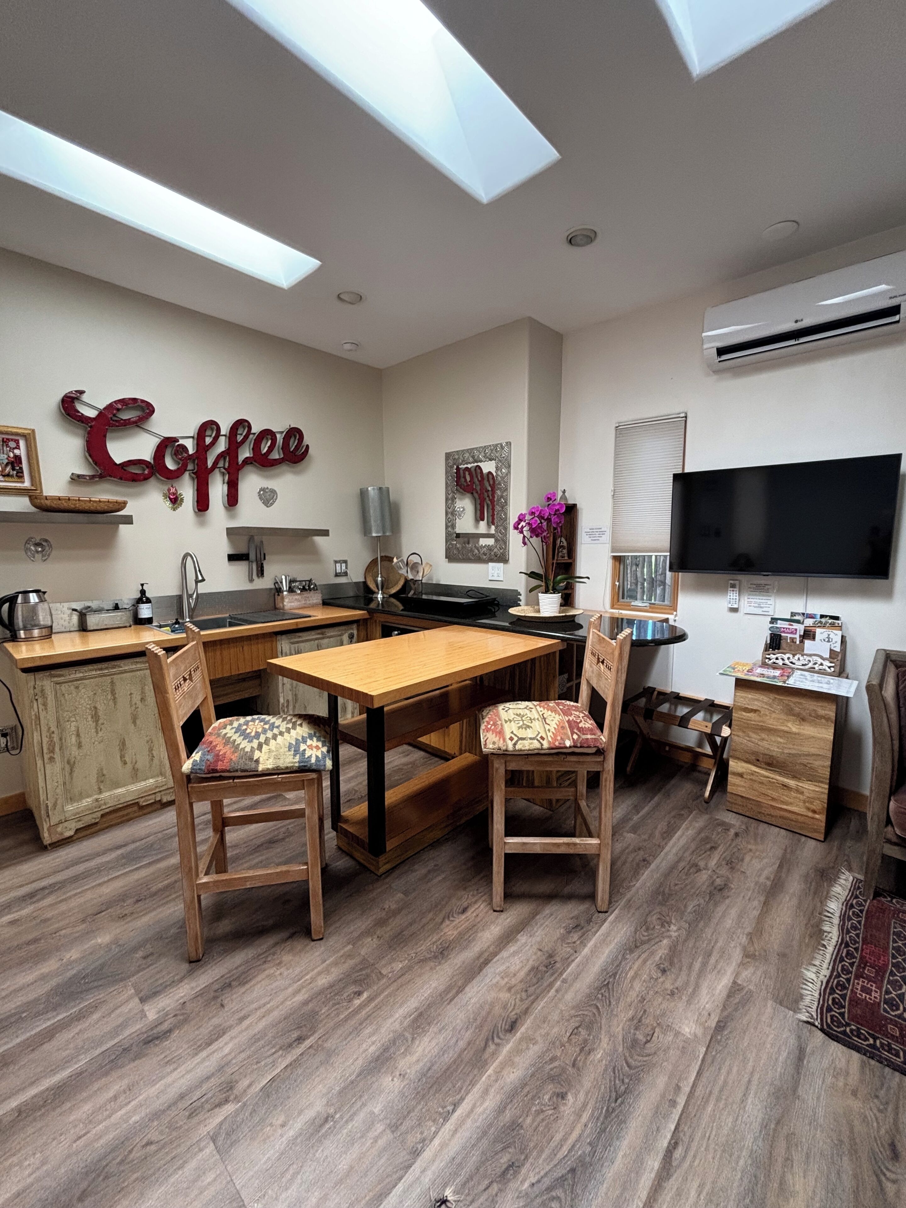 Une cuisine moderne avec un coin repas, un téléviseur et une décoration murale sur le thème du café.