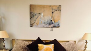 Un lit avec une tête de lit matelassée, deux tables de chevet avec des lampes et un tableau au mur.